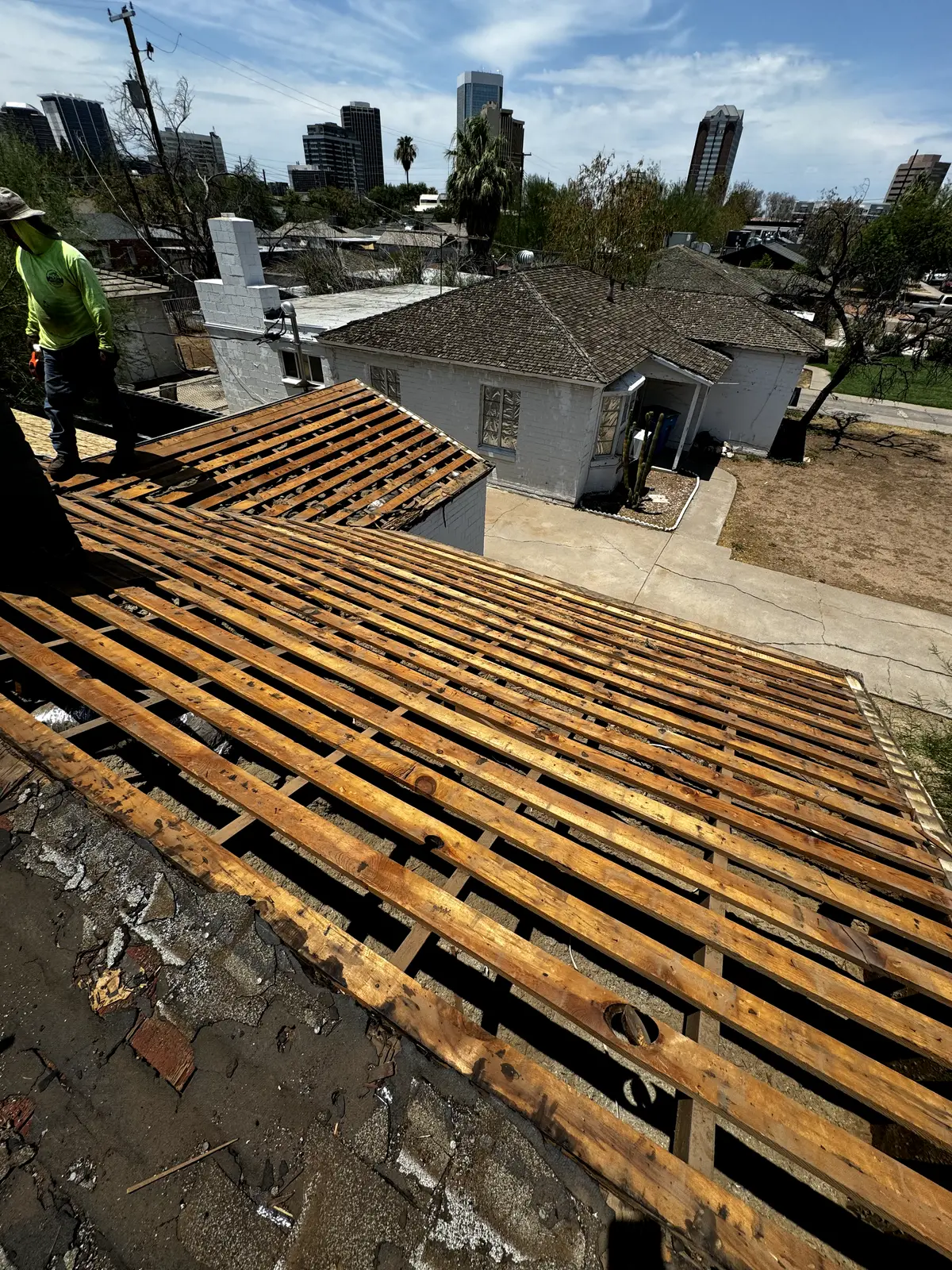 Old skip-sheathing with spaced wood boards and no solid decking exposed during a central Phoenix roof tear-off, by Leal Roofing